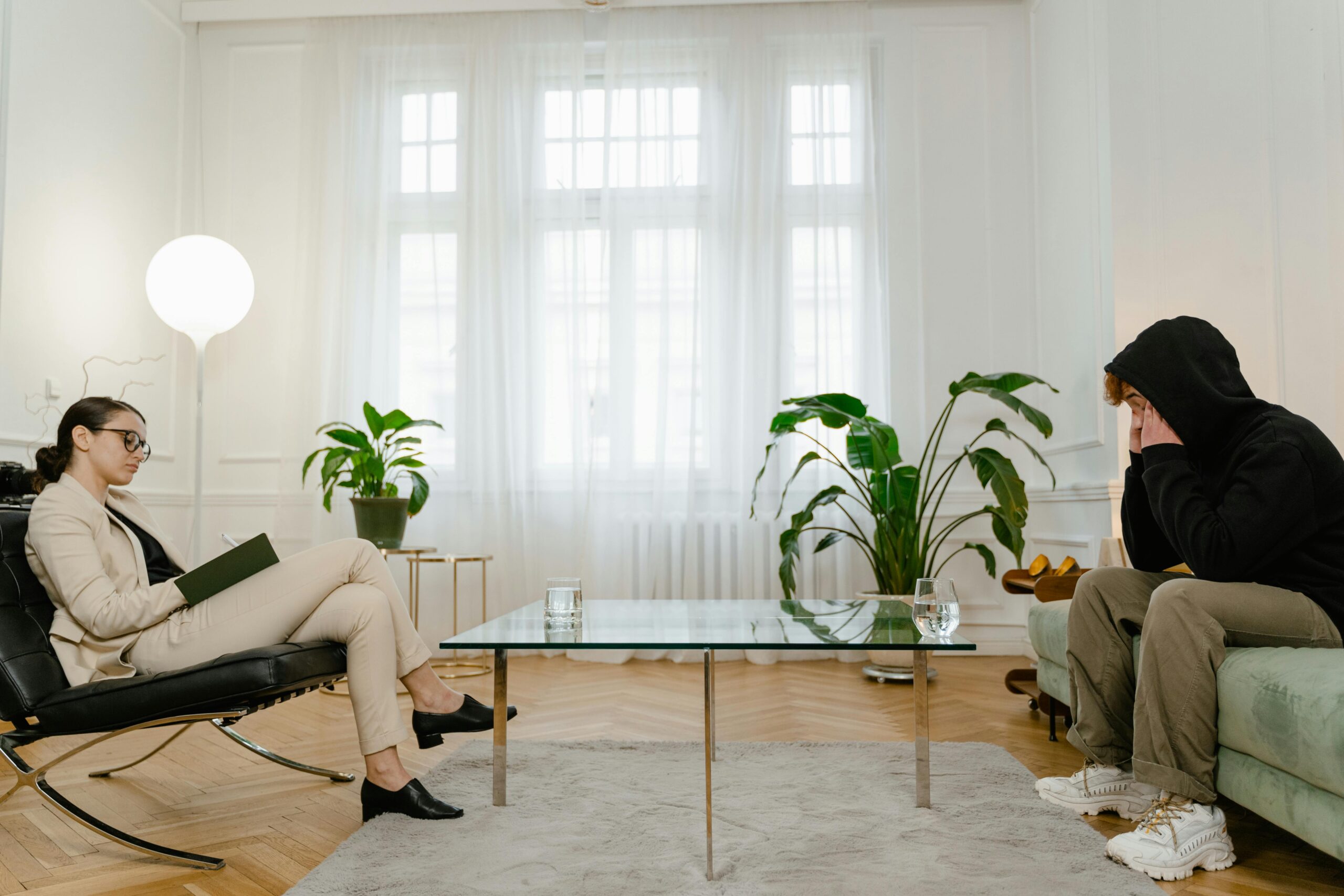 A therapist listens to a patient in a comfortable office setting. The atmosphere is calm and professional.