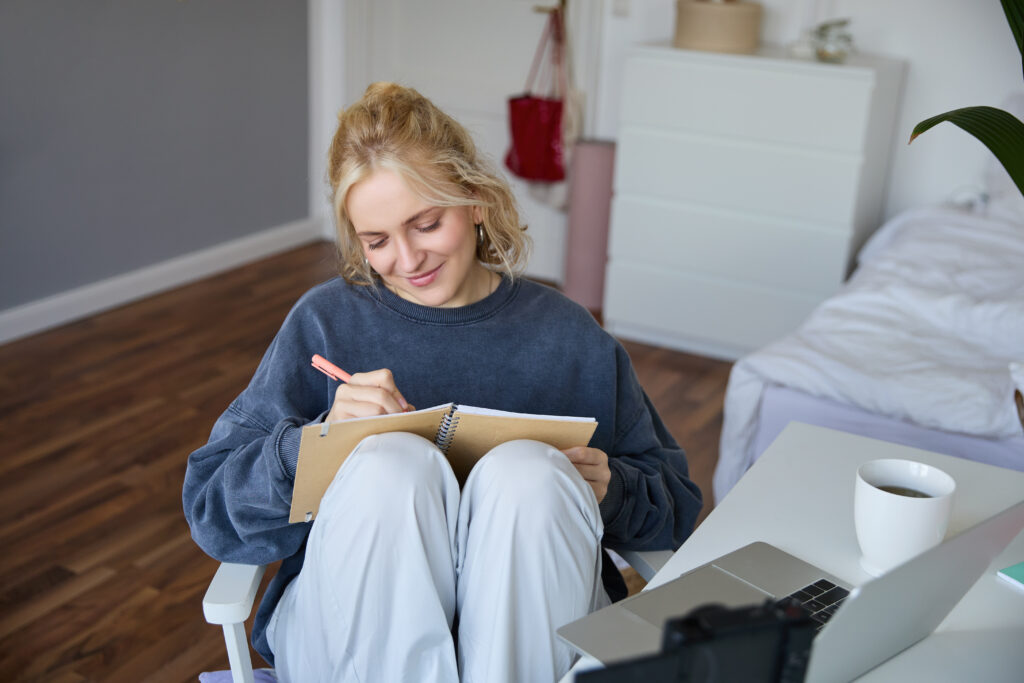 Žena sedi i zapisuje u svesku pri dnevnom svetlu, vežba emocionalne regulacije